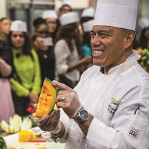 Chef holding a cantaloupe with face carved on the inside