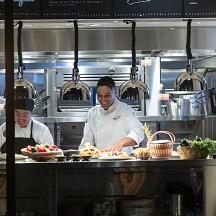 Chef standing behind the kitchen pass with plates of food ready to be served