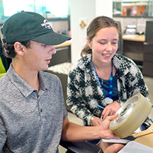 Two college interns at Universal Creative examining a wheel from a ride.