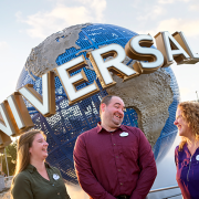 three team members laughing, standing in front of the Universal Globe