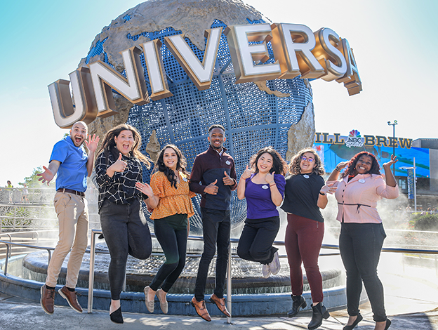 group of team members jumping in front of the universal globe