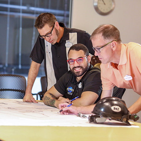 Three engineers working on a draft at a table